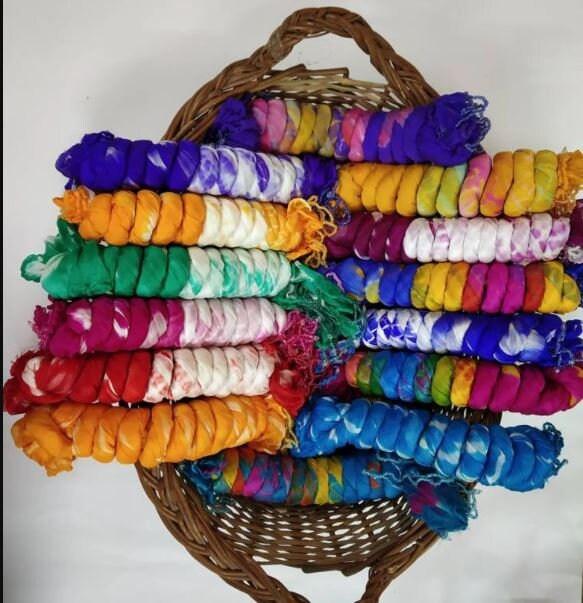 tie and dyed dupattas in a basket for Indian wedding giveaways | Wedifys