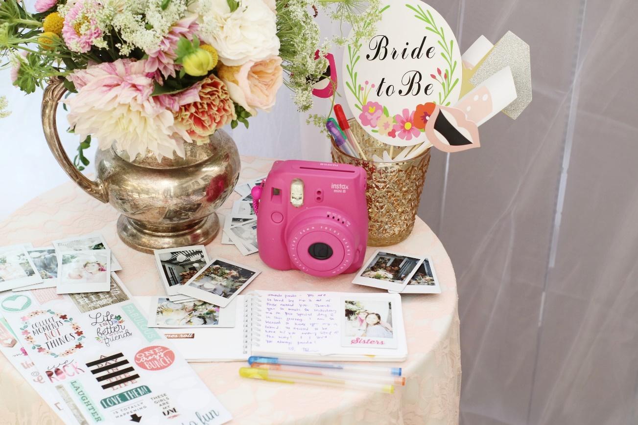 multiple polaroids on a table with a flower bouquet and the Fujifilm Instax Mini 9 camera | Wedifys
