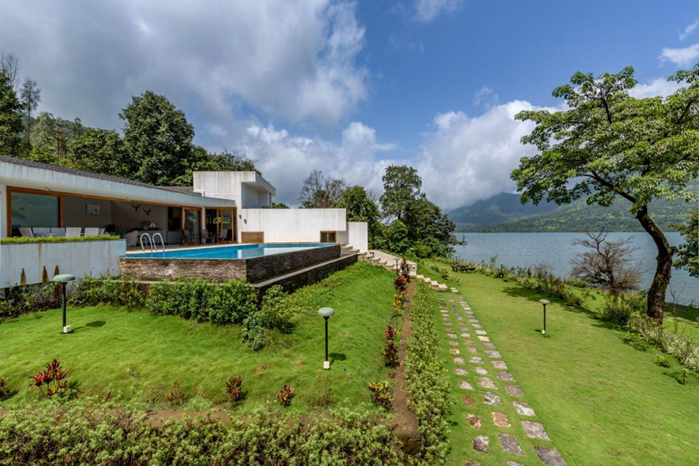an outside picture of the swimming pool and garden of the Bougainvillea Resort & Tanmay Getaways, Mulshi facing a lake | Wedifys
