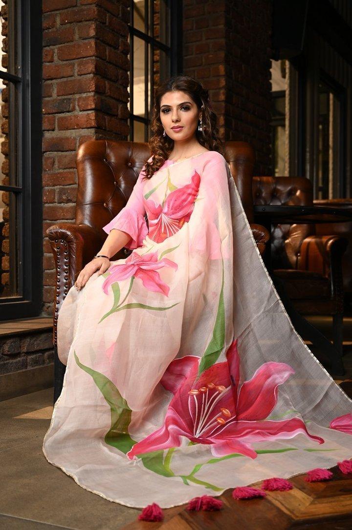 a woman sitting on a chair wearing a pink organza hand painted saree | Wedifys