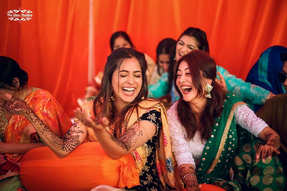 Indian bride and her friend enjoying the mehendi ceremony | Wedifys