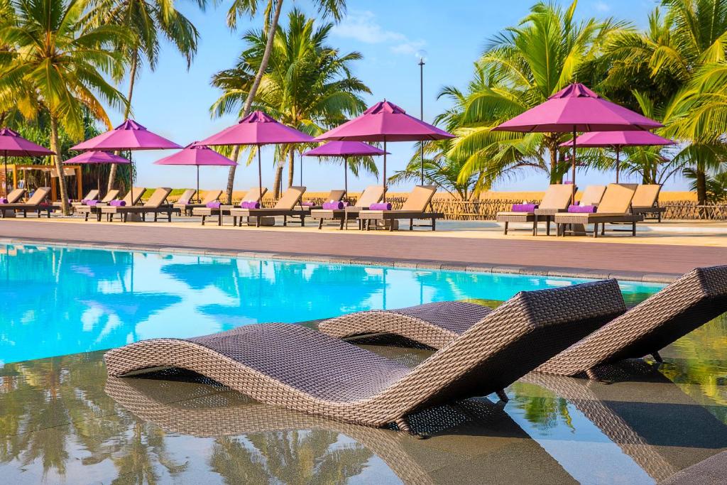 leisure by the pool under flamingo pink umbrellas at AVANI Kalutara Resort in Sri Lanka | Wedifys