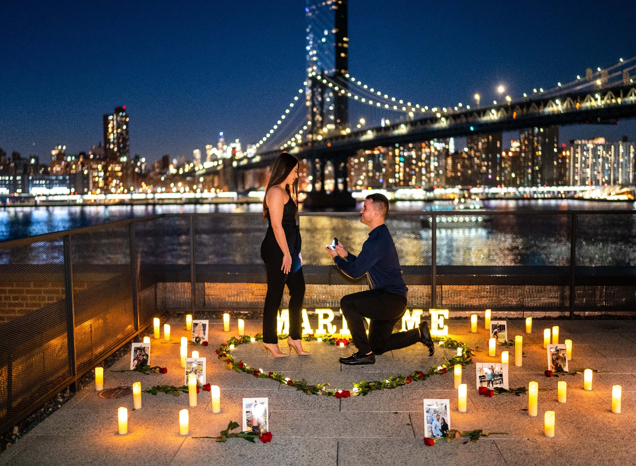 A man proposing in the Brooklyn Bridge Park with the Brooklyn Bridge in background | Wedifys