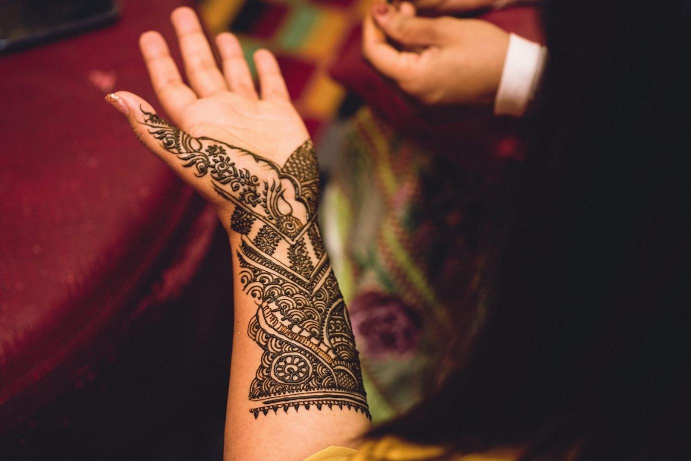 women getting mehndi on their hands for Arti and Ajay’s wedding | Wedifys