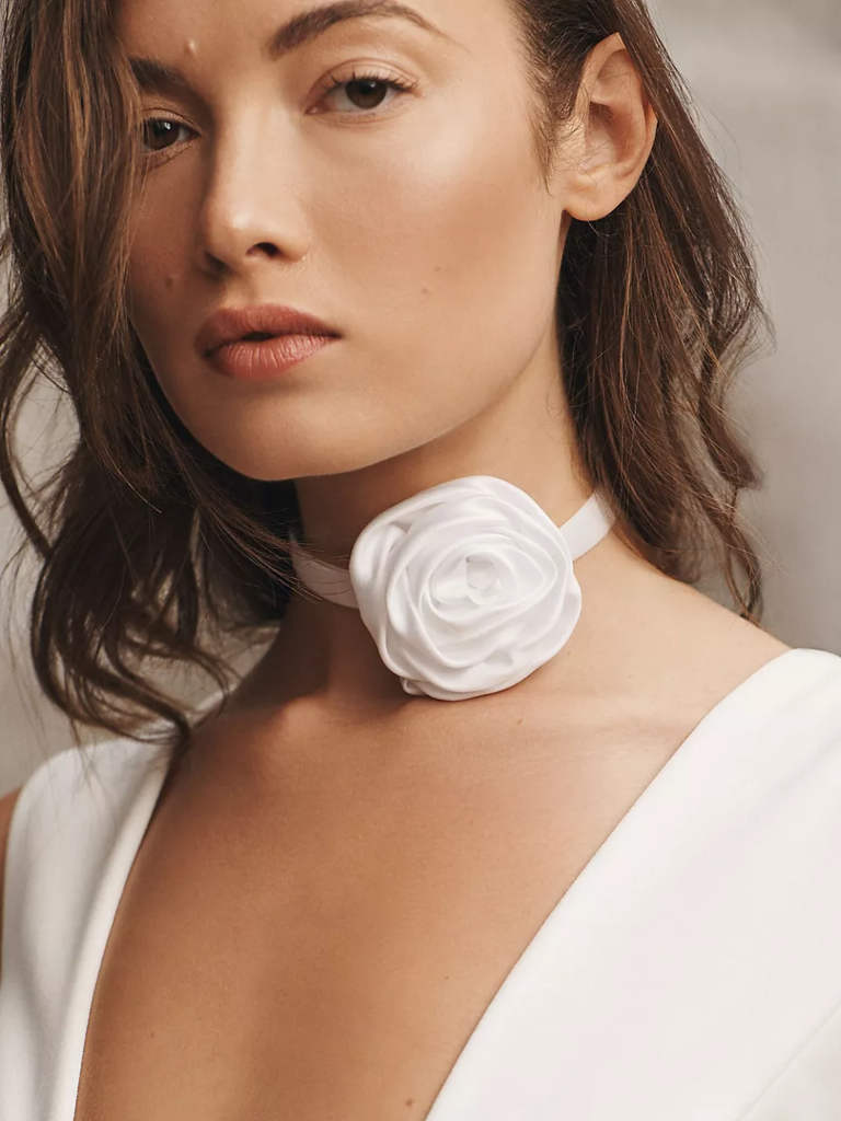a woman wearing a white rosette around her neck | Wedifys