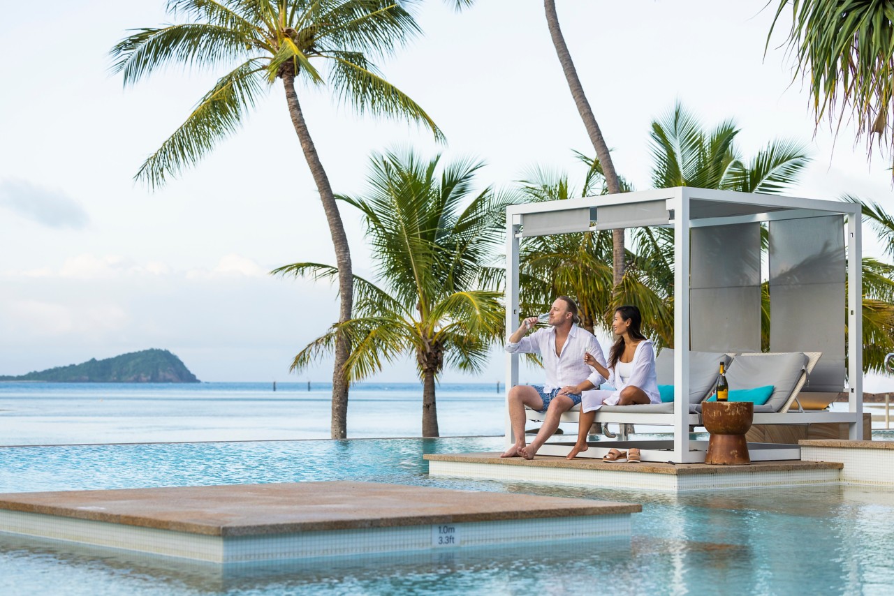a couple sitting in a shed in the pool of Hayman Island Resort | Wedifys