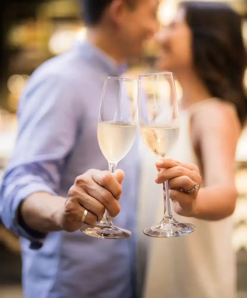 a couple celebrating their engagement with wine | Wedifys